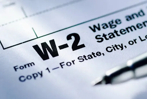 A close-up of a blank W-2 form and a pen.