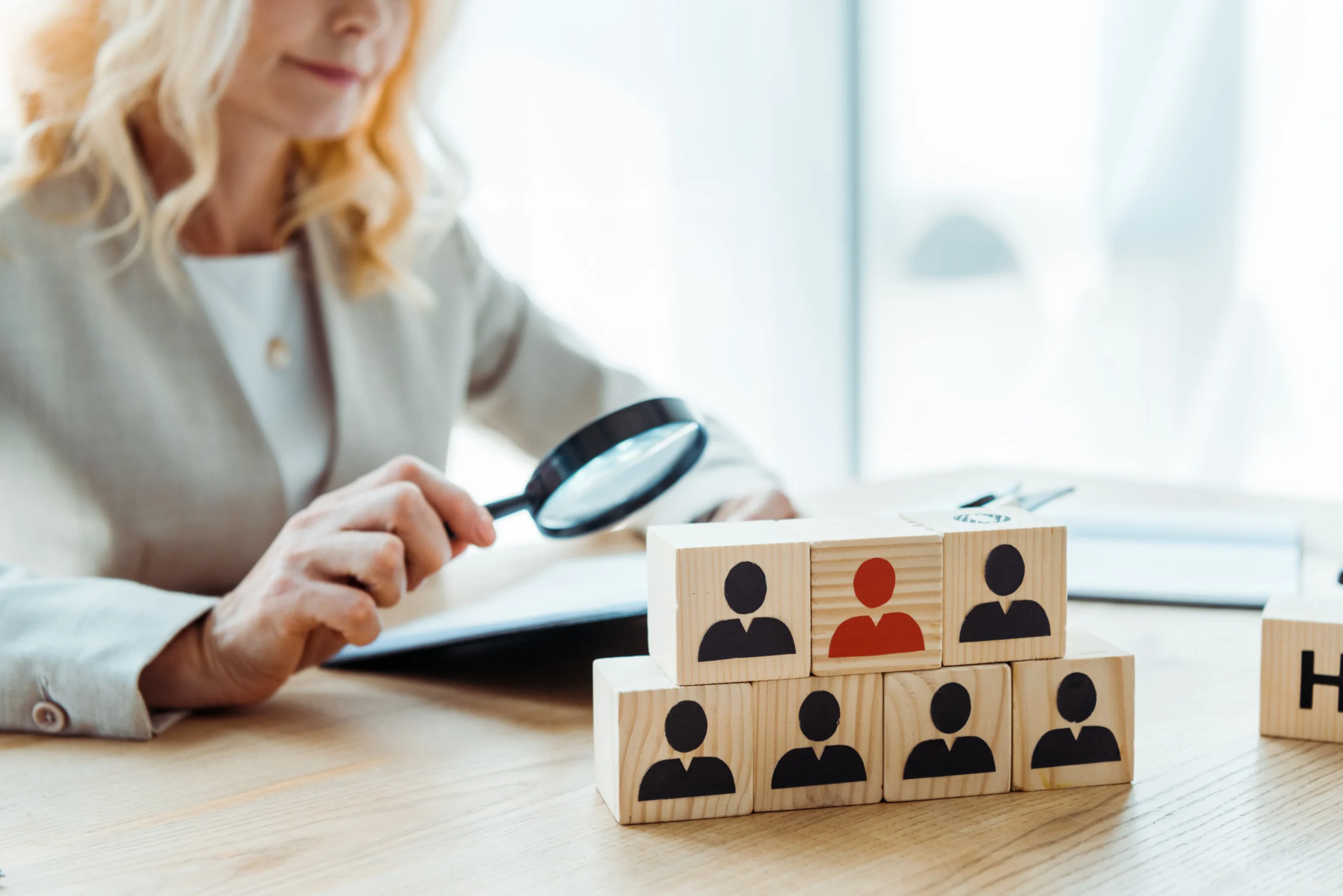 Human Resource Management From Incorp Technical Resources, LLC - Wooden cubes with icons in front of a woman holding a magnifying glass.