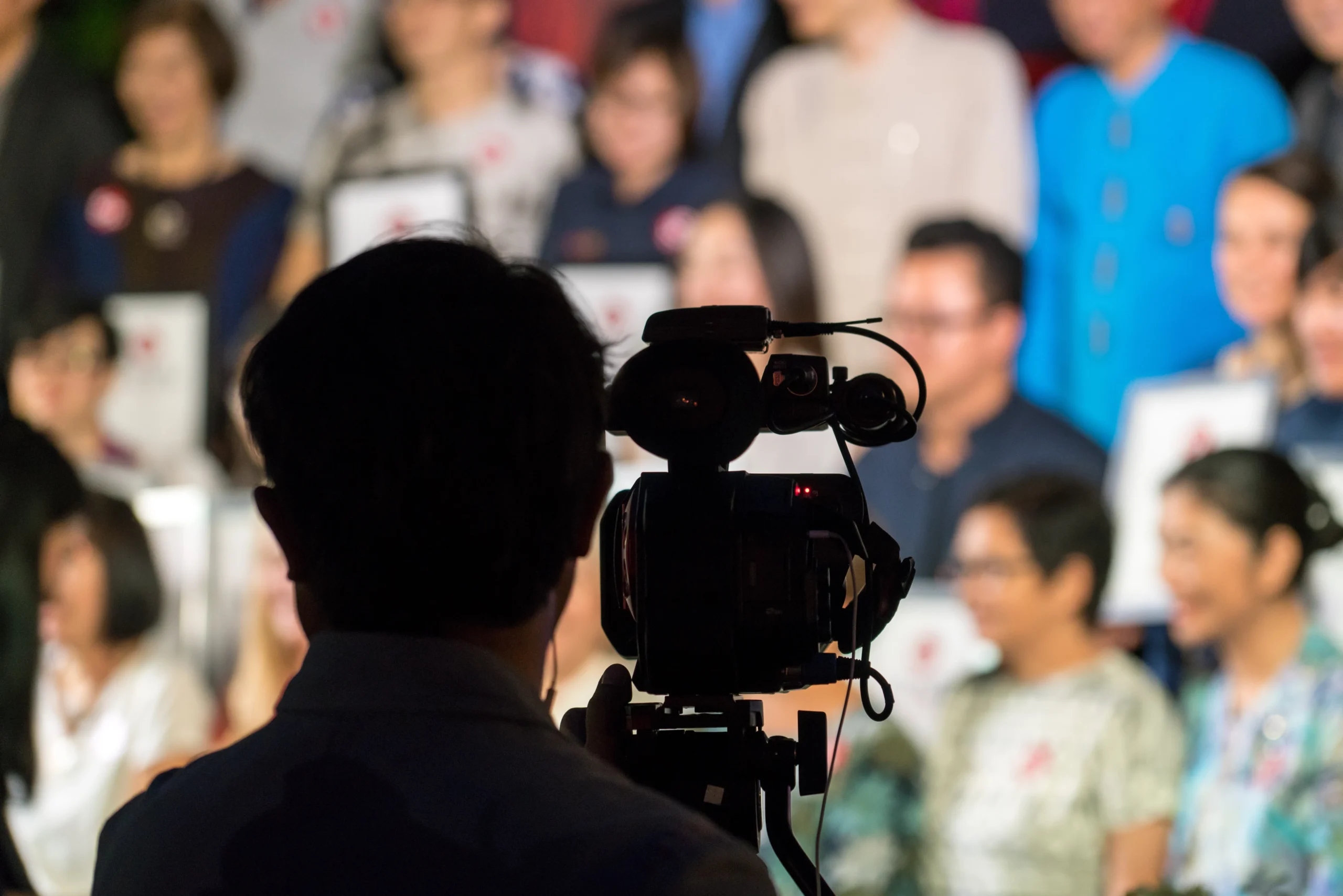 The fast-paced media and entertainment industries require adaptable and efficient human resources services to support their dynamic workforces. - Silhouette of professional cameraman from behind