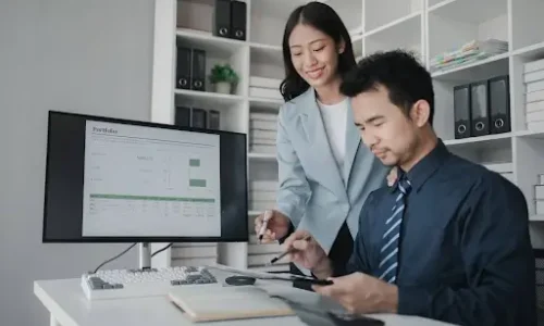 Two employees from the payroll department check the computation on the worksheet.