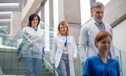 As an employer for independent contractors and gig workers, we ensure they receive the same reliable workers’ comp insurance benefits as traditional employees, helping businesses maintain compliance and peace of mind. - Group of doctors walking down stairs on medical facility