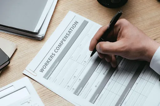 Person writing on a workers compensation form.
