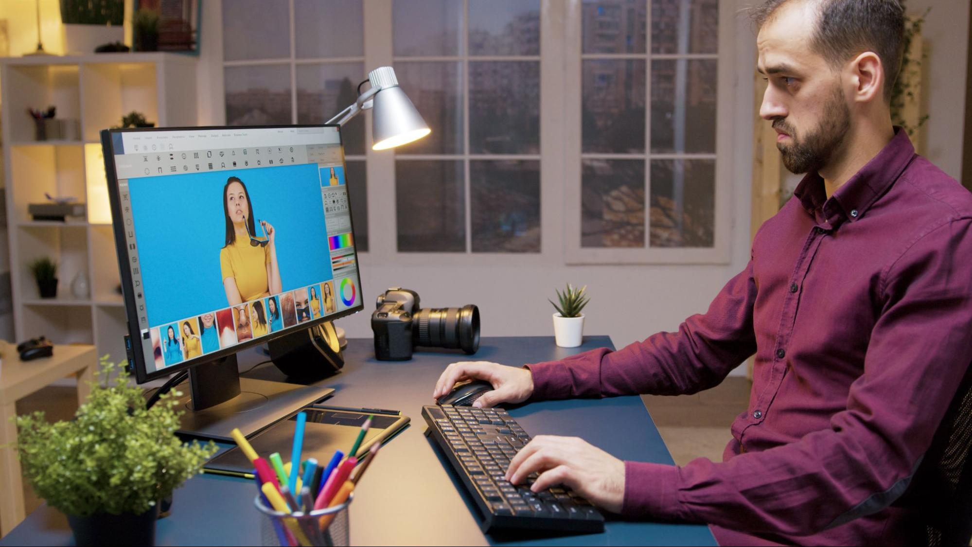 Freelance content creator retouching images in his home-based studio.