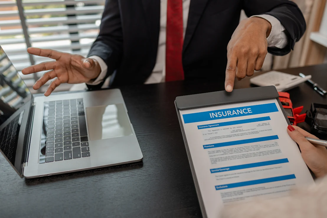An insurance professional points to a contract for a potential client to sign.