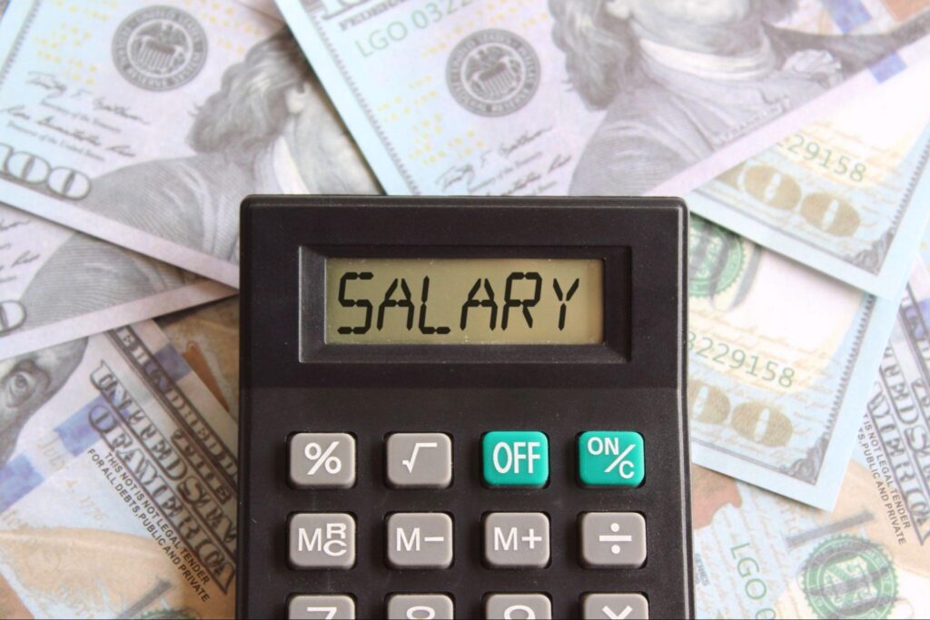 Top view of calculator with 'SALARY' text over US dollar bills.