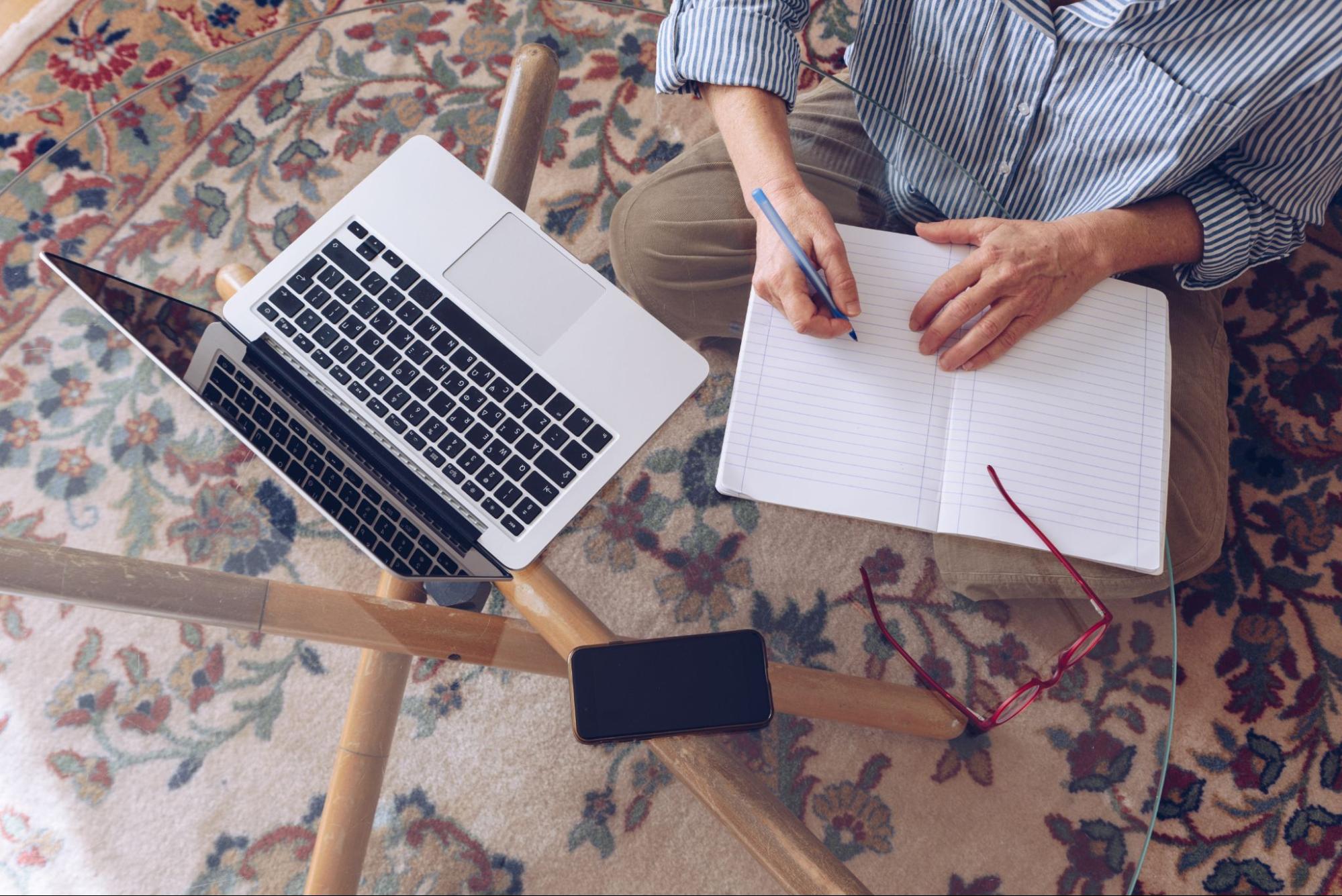 Overhead view of a woman planning freelance work in front of a laptop at home.
