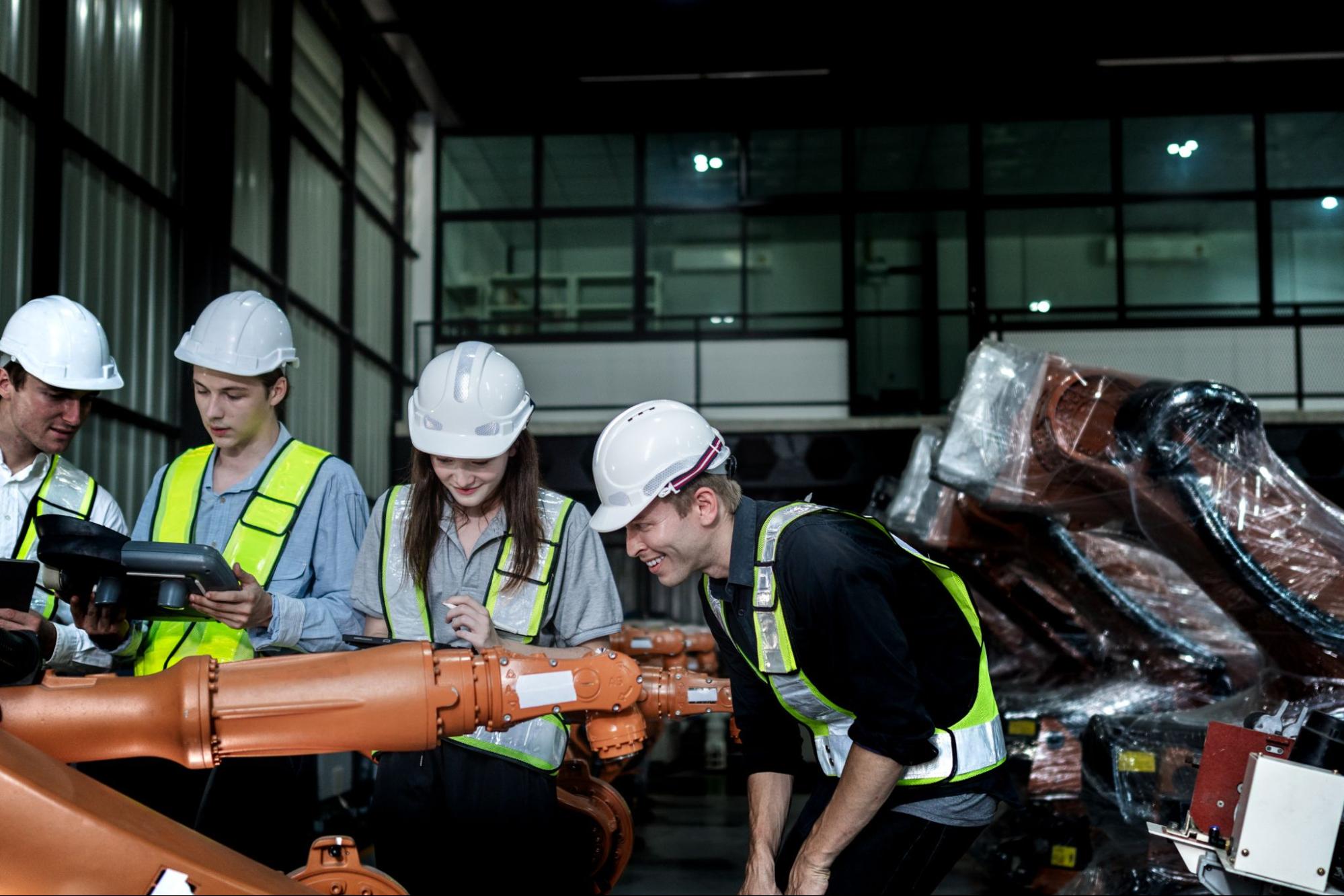 Workers operating a robotic arm in a manufacturing facility