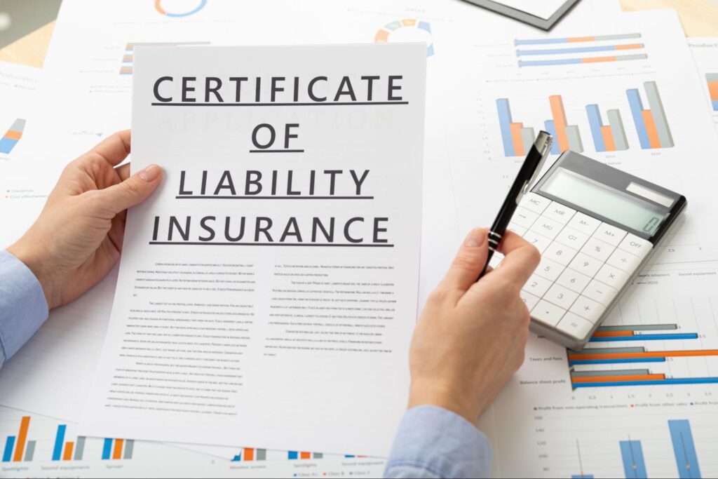 A business owner holding a liability insurance certificate and a pen reviews the documents before signing.