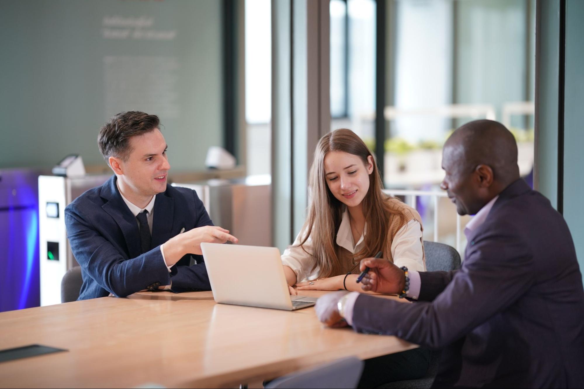 Business professionals reviewing liability insurance documents on a laptop and a touchpad during a team discussion.